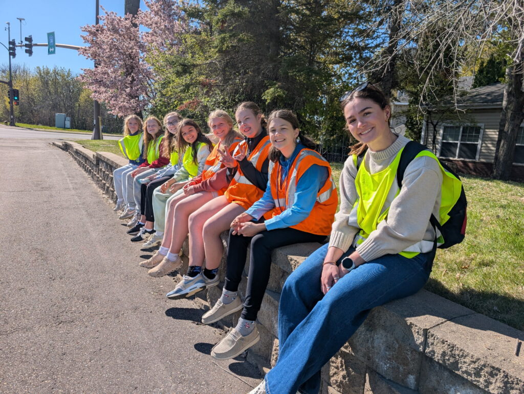 Middle school students wearing safety vests and volunteering together outdoors.